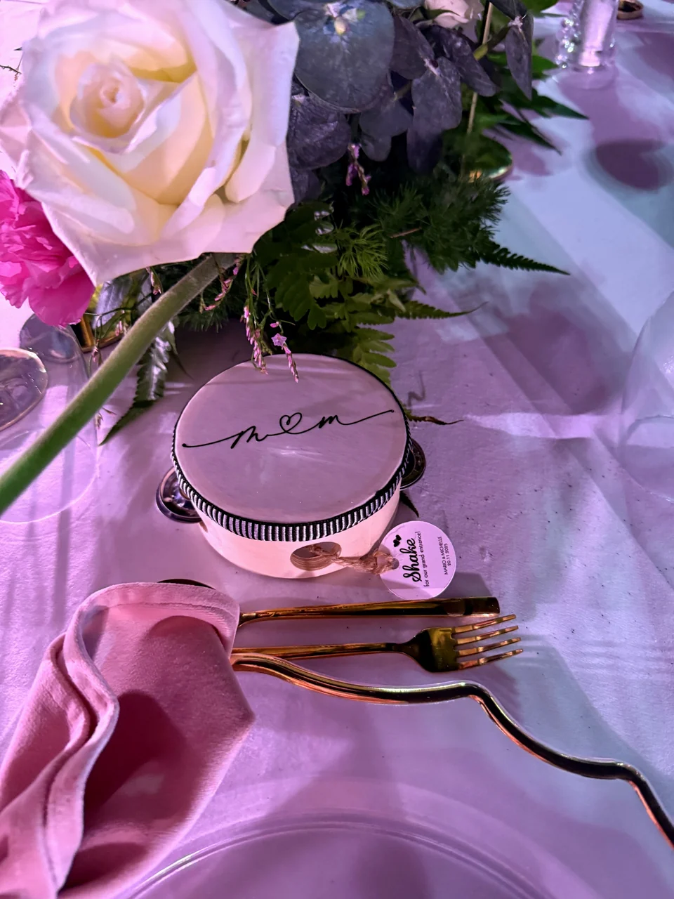 Wedding place setting with a personalised monogram favour, a white rose and gold cutlery