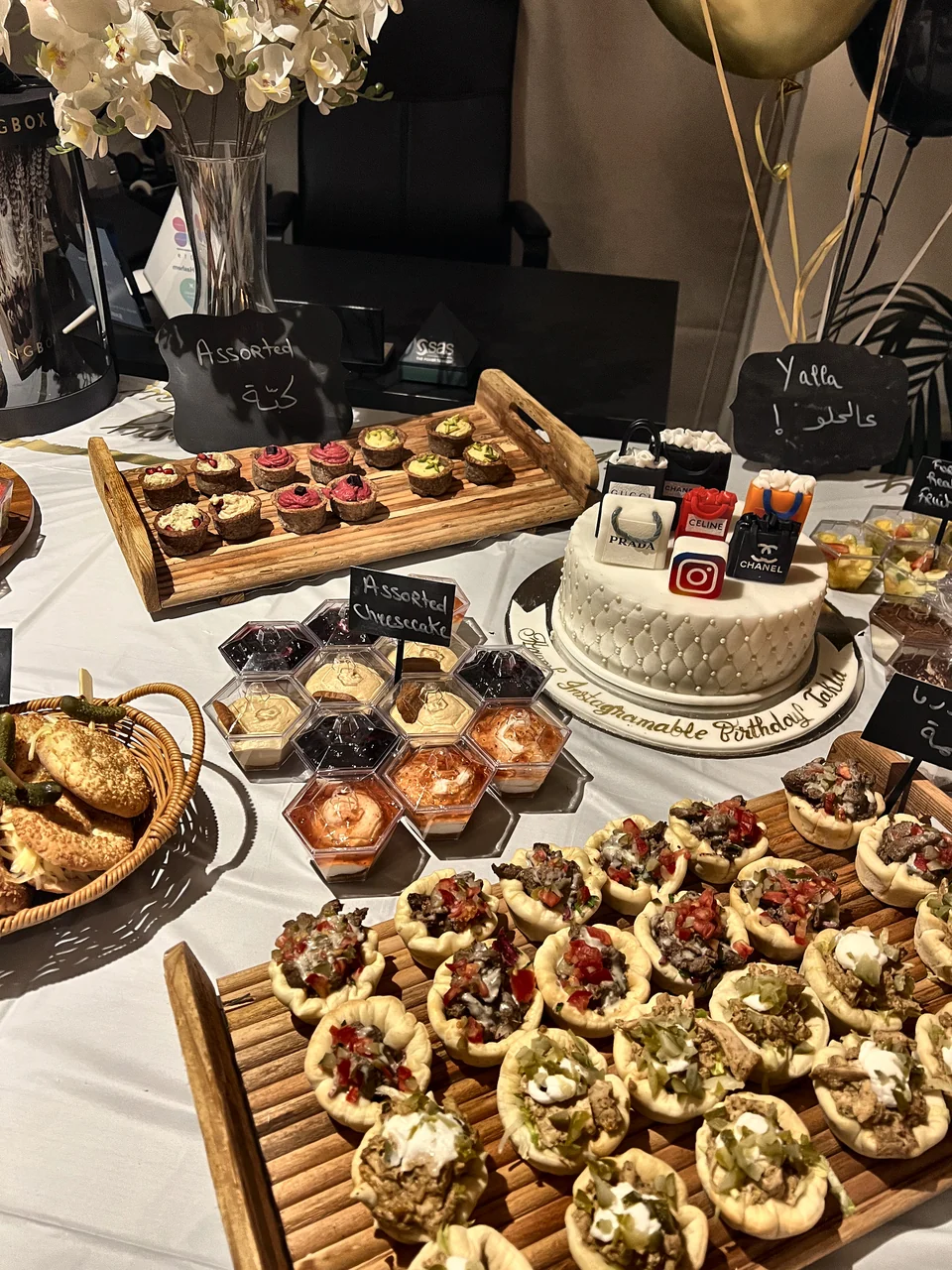 Close-up of the birthday buffet with a white cake, savoury pastries and chalkboard labels