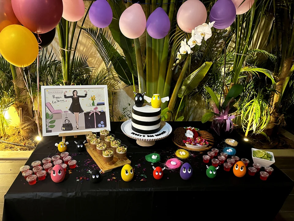Egg shower dessert table with a personalised illustration, a striped cake and colourful egg characters