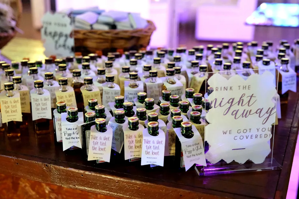 Wedding favours table of personalised mini bottles with a Drink the Night Away sign