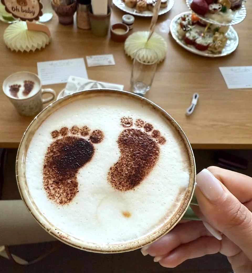Baby footprint latte art at a baby shower, held over the brunch table
