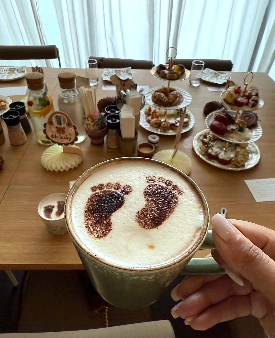 Baby footprint latte art with the baby shower brunch table behind it