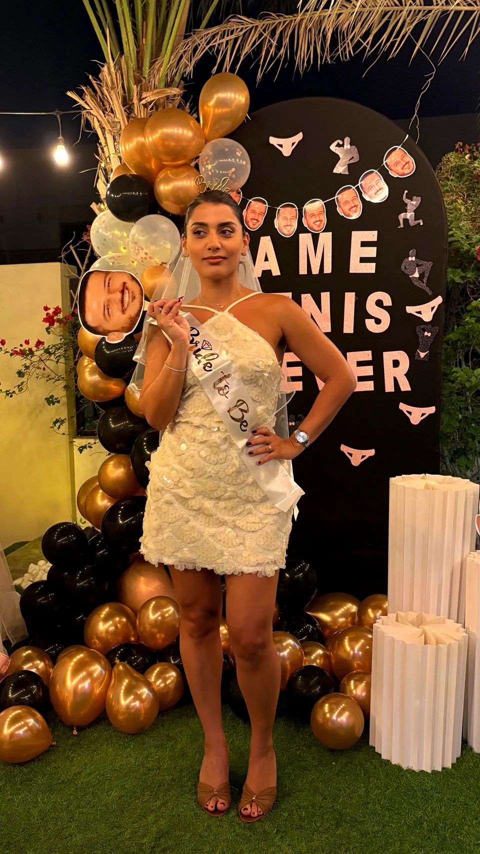 Bride-to-be in a white dress and sash in front of the bachelorette balloon backdrop