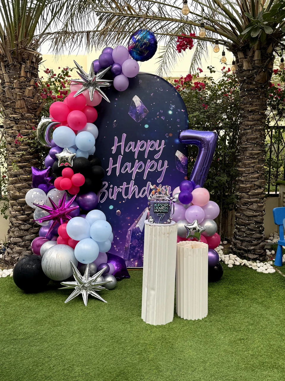 Purple and pink Happy Birthday backdrop with a balloon garland, star balloons and a number seven balloon